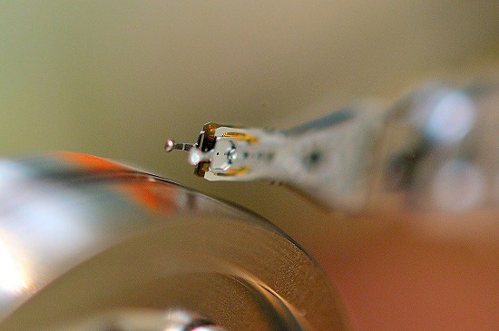 Traditional spinning hard drive head reflected in shiny disk surface